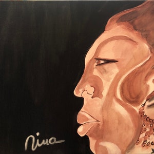 May include: A painting of a person's face in profile, rendered in shades of brown against a black background. The person has a serious expression and is wearing a beaded necklace. The painting is signed "Nina" in the lower left corner.