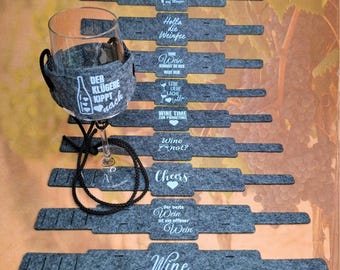 May include: Set of 10 gray felt wine glass charms with white text and heart designs. The charms feature sayings like "Wine Time", "Cheers", "The best wine is an open wine", and "Holla die Weinfee".