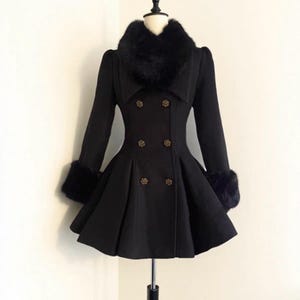 May include: A black coat with a faux fur collar and cuffs. The coat features a double-breasted design with gold-colored buttons and a flared skirt. The coat is displayed on a mannequin, showcasing its elegant silhouette.