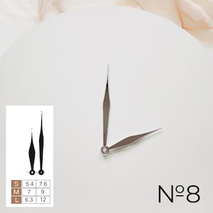 May include: Silver clock hands with a pointed design. The hands are on a white background with the text "N&deg;8" in black.