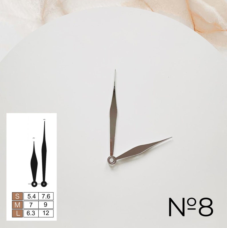 May include: Silver clock hands with a pointed design. The hands are on a white background with the text "N&deg;8" in black.