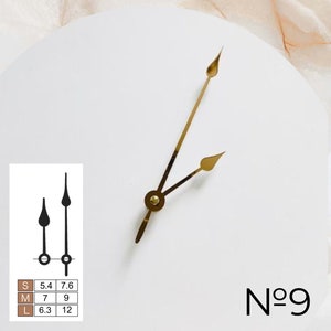 May include: A white clock face with gold hour and minute hands. The clock face has the number "N&deg;9" printed on it.