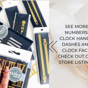 May include: Clock decor items including gold clock hands, Roman numeral numbers, and dashes, packaged in clear plastic. The packaging is black with the "Clock Decor" logo. The text on the image says "See more numbers, clock hands, dashes and clock face, check out our store listings."