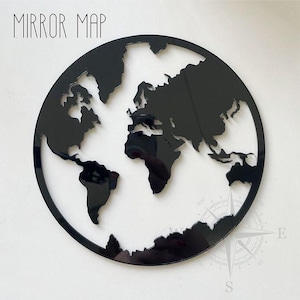 Può includere: Specchio a forma di mappa del mondo in bianco e nero. La mappa è una silhouette dei continenti e degli oceani. Lo specchio è rotondo e ha una cornice nera.