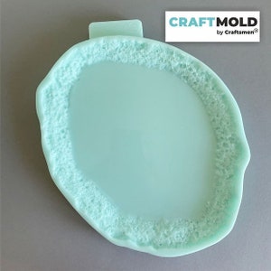 Può includere: Uno stampo in silicone blu chiaro a forma di fetta di agata con un interno liscio e piatto. Lo stampo ha un bordo testurizzato che ricorda la formazione naturale del cristallo. CRAFTMOLD by Craftsmen è stampato nell'angolo in alto a destra dello stampo.