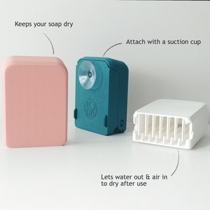 Può includere: Tre portasapone, uno rosa, uno verde acqua con una ventosa e uno bianco con un design a lamelle. Il portasapone verde acqua ha la scritta "HOP" su di esso. La didascalia recita "Keeps your soap dry", "Attach with a suction cup" e "Lets water out & air in to dry after use".