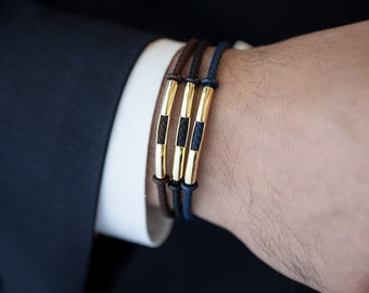 May include: Three leather bracelets with gold accents. The bracelets are brown, black, and blue.