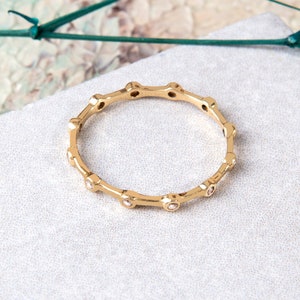 Puede incluir: Un anillo de oro con pequeñas piedras transparentes engastadas en un delicado diseño circular.
