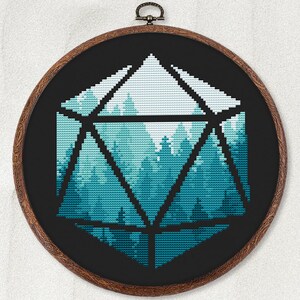 May include: A cross-stitch embroidery hoop with a black background and a blue and white geometric design of a forest scene inside a large, black, outlined, 3D dice shape.