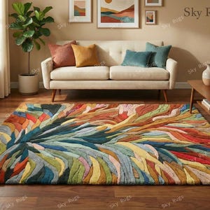 Puede incluir: Una alfombra colorida con un diseño abstracto. La alfombra presenta una mezcla de azules, verdes, amarillos, naranjas y rojos. Se coloca sobre un suelo de madera en un salón, con un sofá y cojines decorativos.