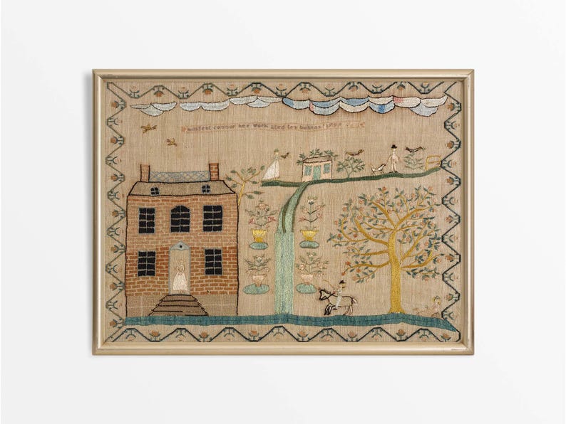May include: Framed antique textile art with an embroidered scene. A brick house, figures, trees, and a waterfall are depicted. The artwork includes text at the top and is framed in a gold-coloured frame.