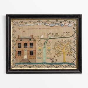 May include: Framed antique textile art showing a house, figures, and a tree. The artwork has a black frame and a beige background with embroidered details in various colours. The text at the top reads "Family is the best".
