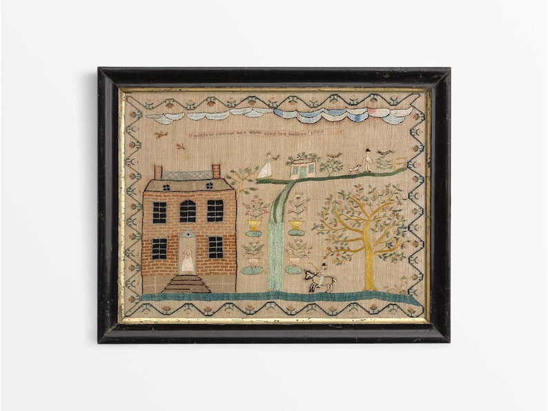 May include: Framed antique textile art showing a house, figures, and a tree. The artwork has a black frame and a beige background with embroidered details in various colours. The text at the top reads "Family is the best".