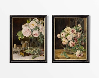 May include: Two framed floral still life paintings. The left painting features pink roses in a vase, a silver goblet, a candle, and a book. The right painting shows a bouquet of roses in a glass vase.