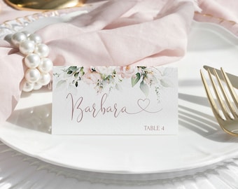 May include: A white place card with a floral design and the name "Barbara" and "Table 4" printed on it. The place card is sitting on a white plate with a gold rim.