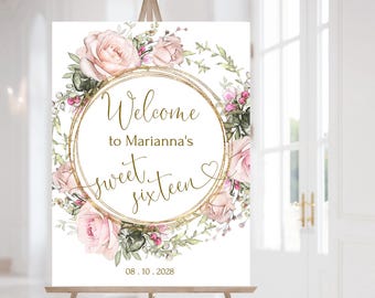 Puede incluir: Un letrero blanco sobre un caballete de madera con el texto "Welcome to Marianna's sweet sixteen" en letras doradas. El texto está rodeado por un marco circular dorado y una corona floral de rosas rosas y vegetación. La fecha "08.10.2028" está en la parte inferior.