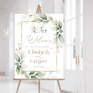 Könnte beinhalten: Ein Hochzeits-Willkommensschild auf einer Staffelei. Das Schild hat einen goldenen Rahmen mit floralen und grünen Akzenten. Der Text lautet "Welcome to our wedding Elisabeth and Gregory 07|01|2028".