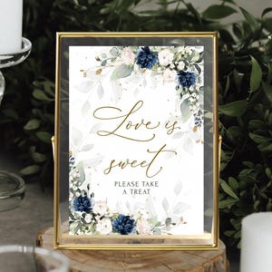 Könnte beinhalten: Ein goldfarbener Rahmen mit einem weißen Hintergrund und einem Aquarell-Blumendesign in Blautönen und Grün. Der Text auf dem Schild lautet "Love is sweet. Please take a treat."