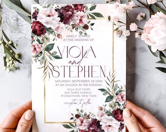 May include: Wedding invitation with a floral design featuring burgundy and pink flowers. The invitation is framed with a gold border and includes the names "Viola and Stephen" and the wedding date and location.