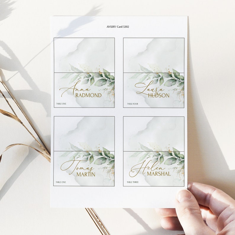 May include: Four place cards with a watercolor background and gold lettering. The names on the cards are Anna Radmond, Laura Hudson, Tomas Martin, and Helen Marshal.