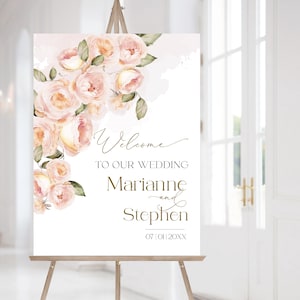May include: A white wedding welcome sign with a floral design in shades of pink and green. The text reads "Welcome to our wedding Marianne and Stephen 07|01|20XX".