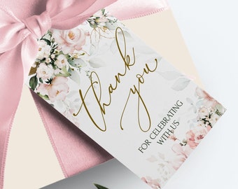 May include: A white thank you gift tag with a floral design in shades of pink and green. The text "Thank you" is written in gold script. The tag also includes the text "For celebrating with us".