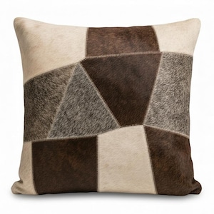 Puede incluir: Cojín decorativo cuadrado con diseño de patchwork. El cojín presenta varias formas geométricas en tonos marrón, beige y gris. Las texturas parecen ser una mezcla de materiales lisos y texturizados, creando un patrón visualmente interesante.