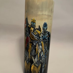 May include: A yellow and black Transformers character, Bumblebee, stands with a blue and silver Transformers character. The characters are on a black and white background with a cloudy sky.