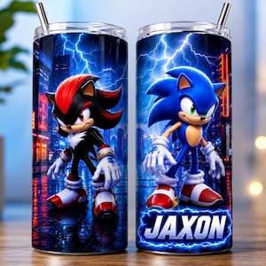 May include: Two cylindrical metal tumblers with clear lids and metal straws. The left tumbler features Shadow the Hedgehog against a dark city background with lightning. The right tumbler features Sonic the Hedgehog and the name JAXON in white text.