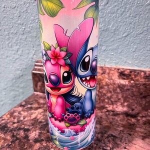 May include: A stainless steel tumbler with a colorful design featuring Stitch and Angel from the Disney movie Lilo & Stitch. The design includes tropical leaves, flowers, and ocean waves.
