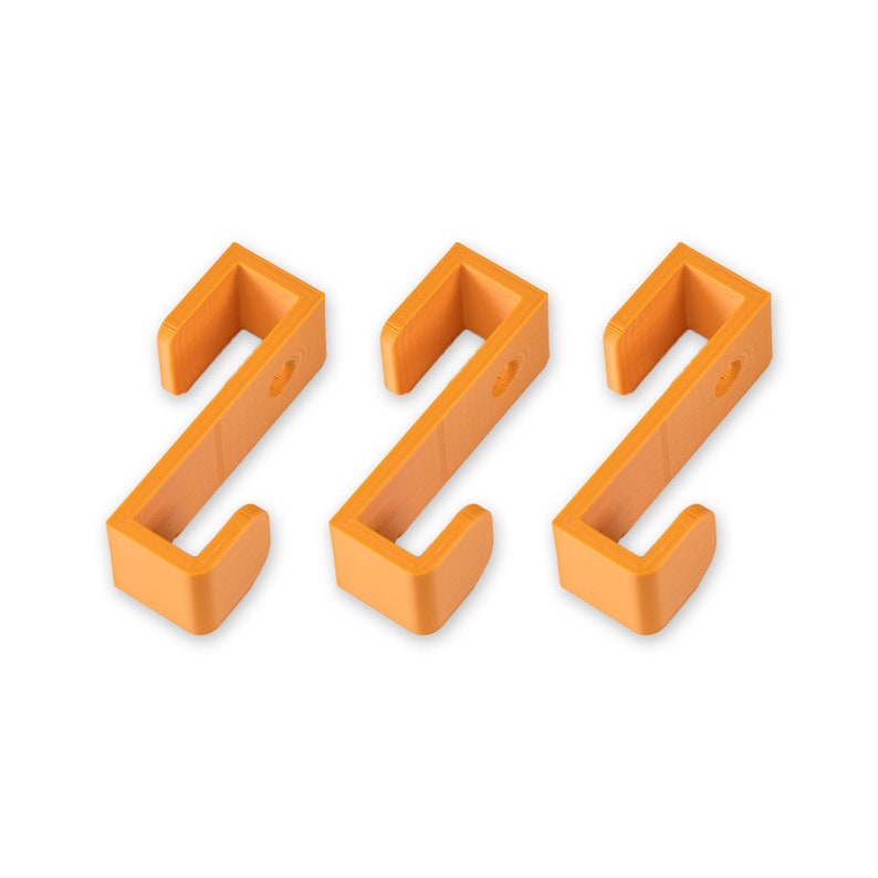 May include: Three orange plastic hooks, each with a simple S-shape design. The hooks are ideal for hanging lightweight items.