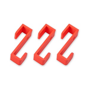 May include: Three bright red plastic hooks, each with a simple, curved design. The hooks are ideal for hanging lightweight items.