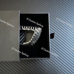 May include: A black carbon fiber key fob in a black box with the text "H Custom Sydney" printed on the box.