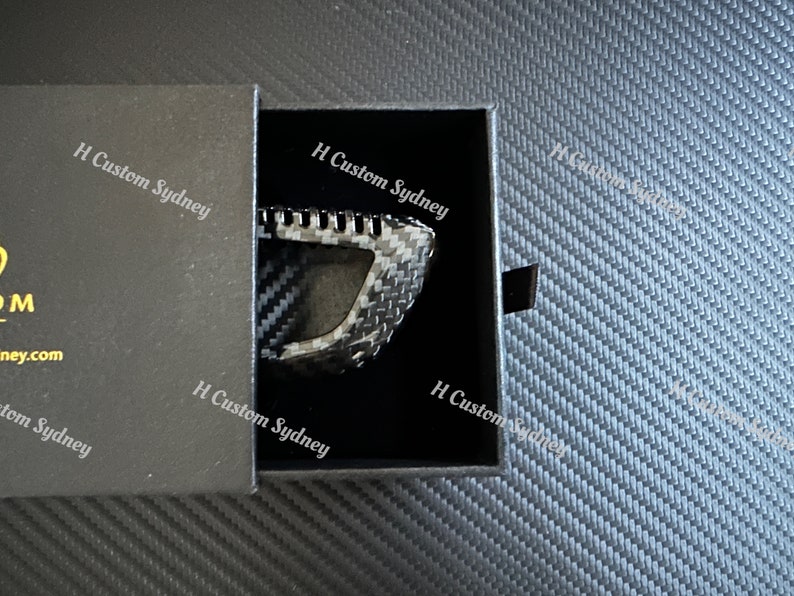 May include: A black carbon fiber key fob in a black box with the text "H Custom Sydney" printed on the box.
