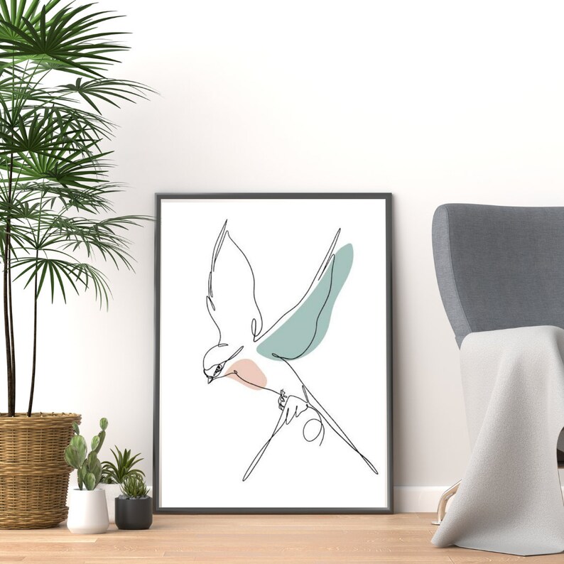 May include: A black framed print of a minimalist line drawing of a bird in flight with a light blue and pink color wash. The bird is flying to the right with its wings spread.
