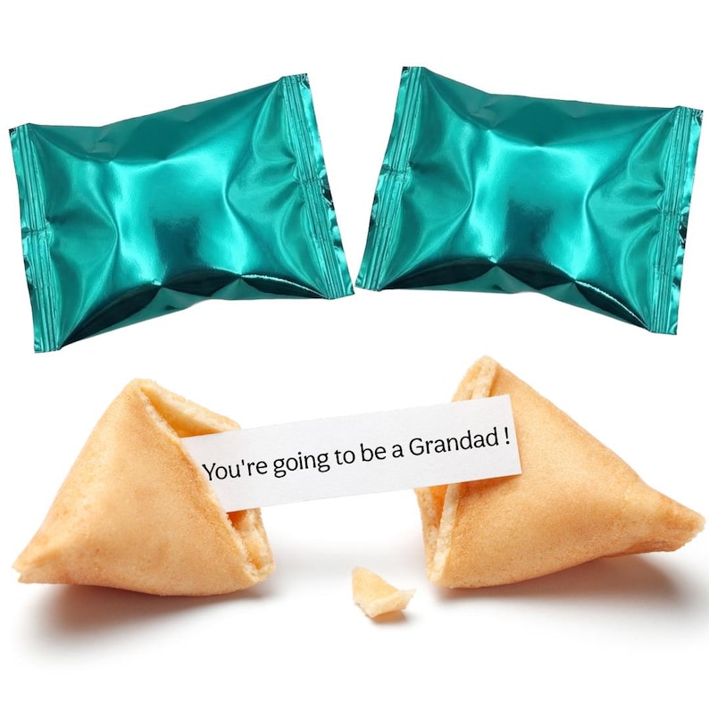 Pu&ograve; includere: Due biscotti della fortuna, uno rotto, con un messaggio che dice "You're going to be a Grandad!". Due caramelle avvolte in carta stagnola turchese sullo sfondo. I biscotti sono marrone dorato.