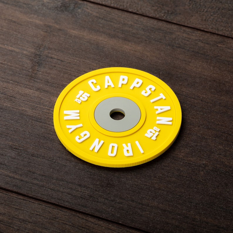 Pode incluir: Placa de peso amarela com o texto "IRON GYM CAPSTAN 1.25 KG" em letras brancas.