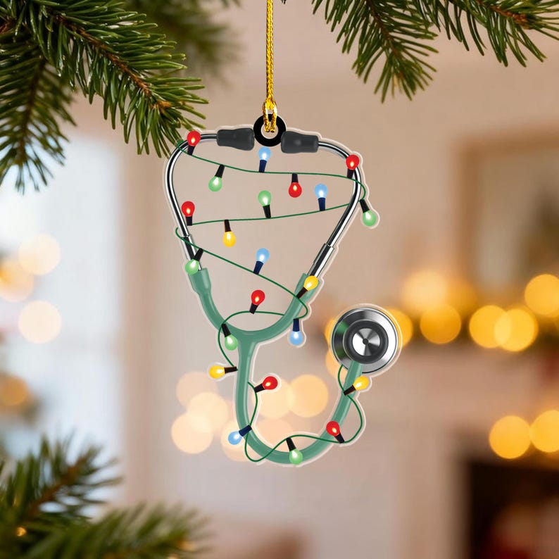 May include: A Christmas tree ornament shaped like a stethoscope, with a green handle and a silver head. The stethoscope is decorated with colorful Christmas lights. The ornament hangs from a gold string.