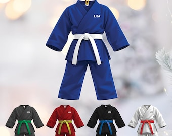 May include: A blue karate uniform ornament with a white belt and the name "LISA" printed on the chest. Below are four additional ornaments in black, red, black, and white, each with a different colored belt.