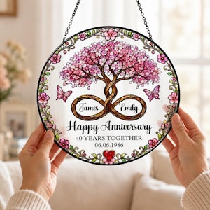 May include: A circular stained glass suncatcher featuring a pink cherry blossom tree with intertwined trunks forming an infinity symbol. The text reads James, Emily, Happy Anniversary, 40 YEARS TOGETHER, and 06.06.1986, with two butterflies and a red heart.