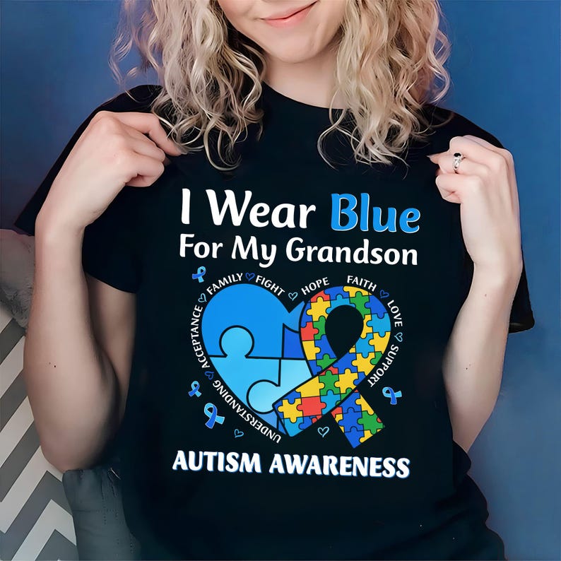 May include: Black t-shirt with the text "I Wear Blue For My Grandson" in white and blue. The shirt features a blue puzzle piece heart and a ribbon made of puzzle pieces, with the words "Autism Awareness" at the bottom.