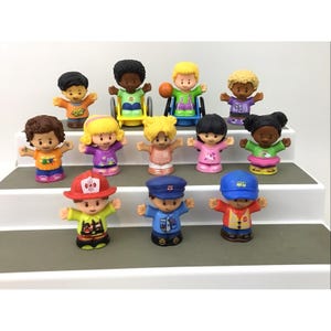 May include: A collection of twelve small plastic toy figures arranged in three rows. The figures feature diverse skin tones, hair colors, and clothing styles, including two figures in wheelchairs, a firefighter, a police officer, and a bus driver.