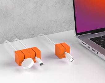 May include: Orange cable organizers with white cables and connectors. One organizer holds three cables, and the other holds one. A white Apple Watch charger and a laptop are also in the image.