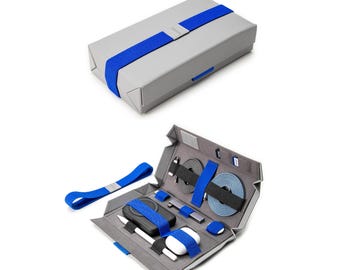 May include: A gray travel case with a blue strap, open to reveal a set of tech accessories including a power bank, charging cables, and a stylus.