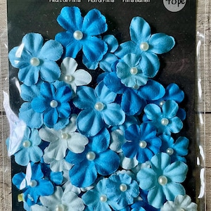 May include: A package of Prima Flowers, featuring 48 handmade paper flowers in shades of blue and white. Each flower has a pearl center. The package has the text "Prima Flowers" and "48 pc".