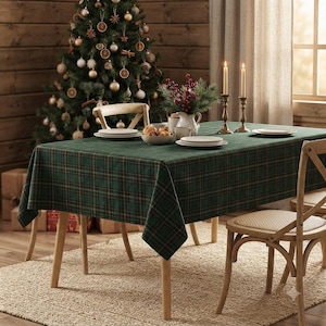 May include: A rectangular dining table covered with a dark green plaid tablecloth. The table is set with white plates, a bowl of food, and a white pitcher containing red berries. Two tall brass candlesticks with lit candles stand on the table.