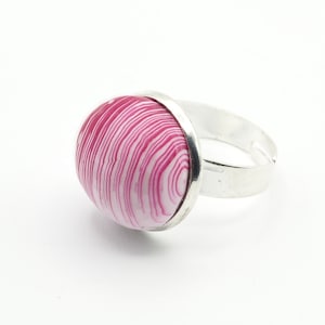 Può includere: Un anello d'argento con un cabochon a spirale rosa e bianco.