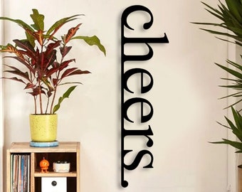 May include: Black metal wall decor with the word "cheers" written vertically. The decor is hanging on a white wall above a record player and a shelf with records and books.