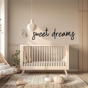 May include: A nursery scene with a light-colored crib, a decorative wall hanging that says "sweet dreams", and a hanging light fixture. The room has a neutral color palette with wooden flooring and a rug.