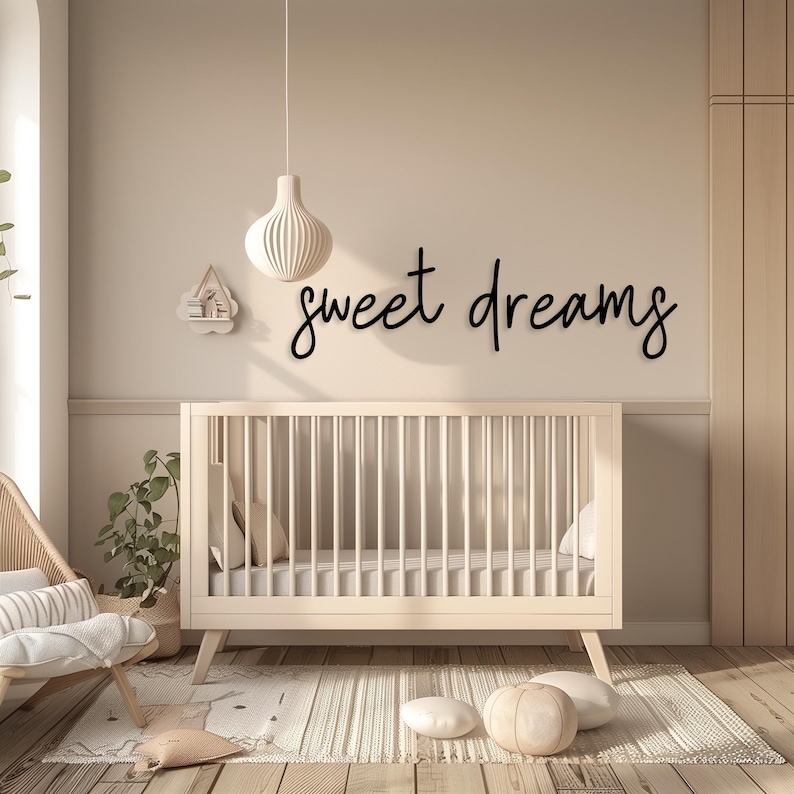 May include: A nursery scene with a light-colored crib, a decorative wall hanging that says "sweet dreams", and a hanging light fixture. The room has a neutral color palette with wooden flooring and a rug.